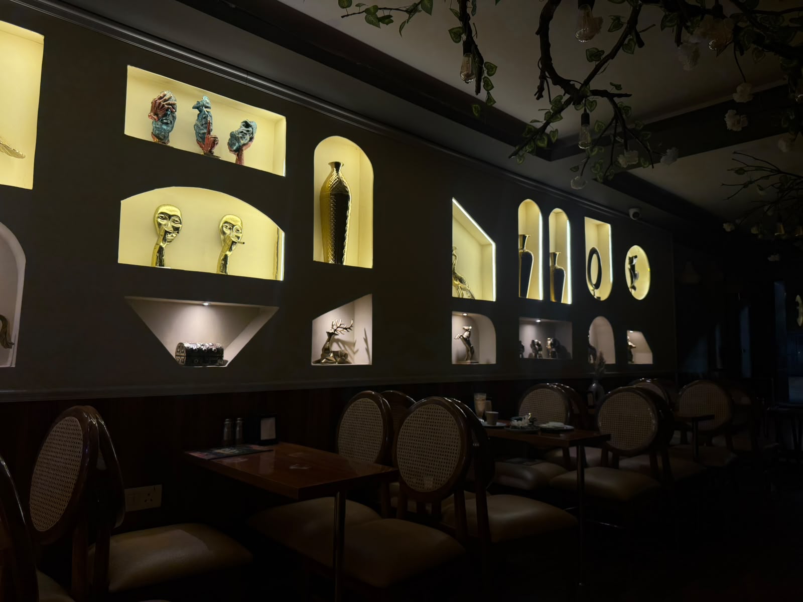 Warm cafe interior with brass sculptures in arched niches